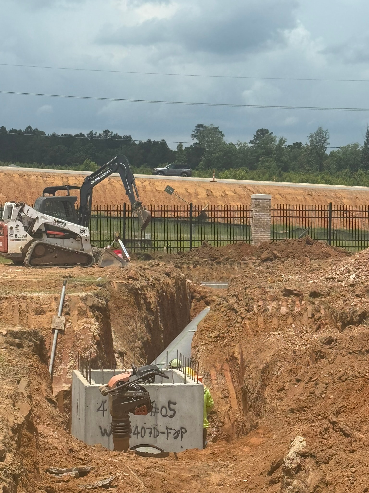 Bobcat and excavator setting catch basin CB-05 with crew