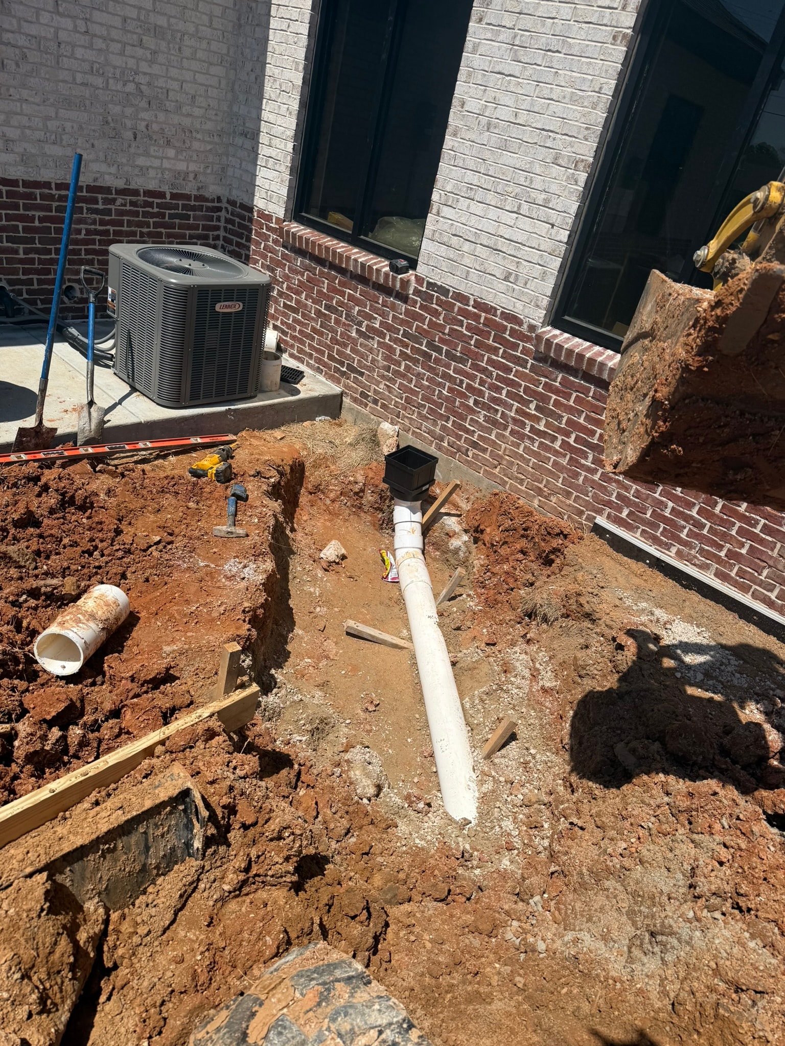 Drainage pipe run along brick building wall in open trench